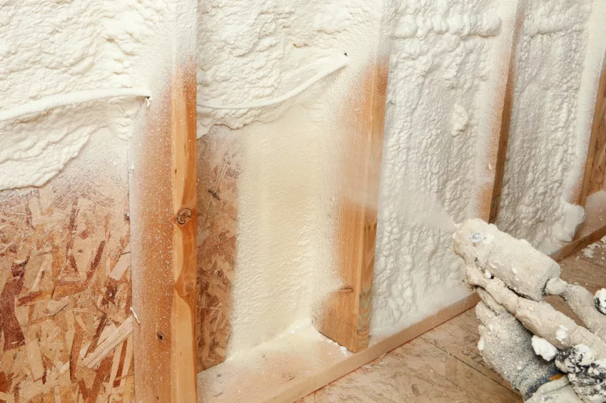 Interior wall insulation with fiberglass batts between wooden studs and drywall.