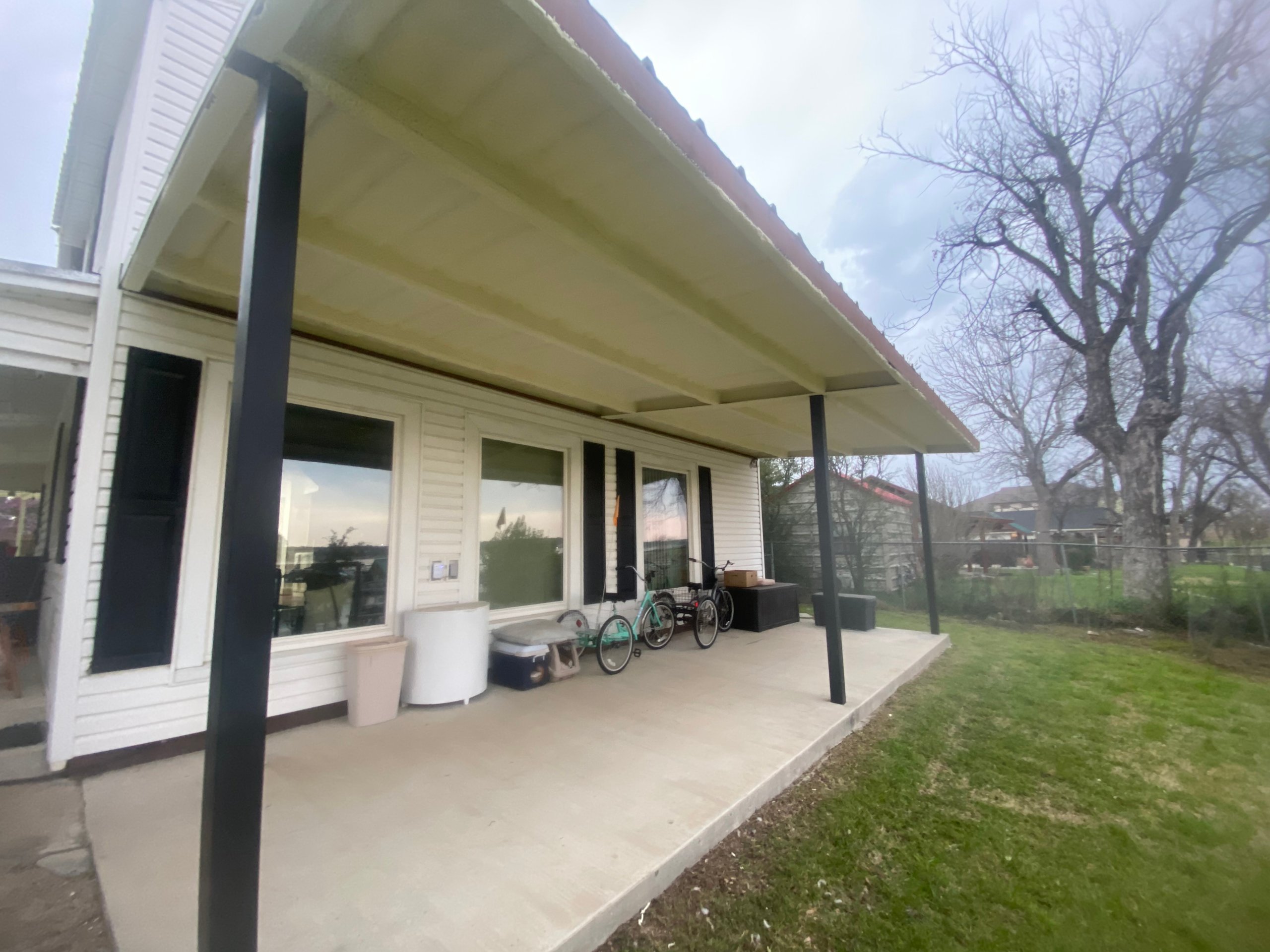 Modern house with cream awning, concrete patio, bicycles, and bare tree in background