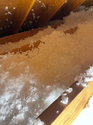 Wooden beams support a flooded surface with muddy water and white foam residue